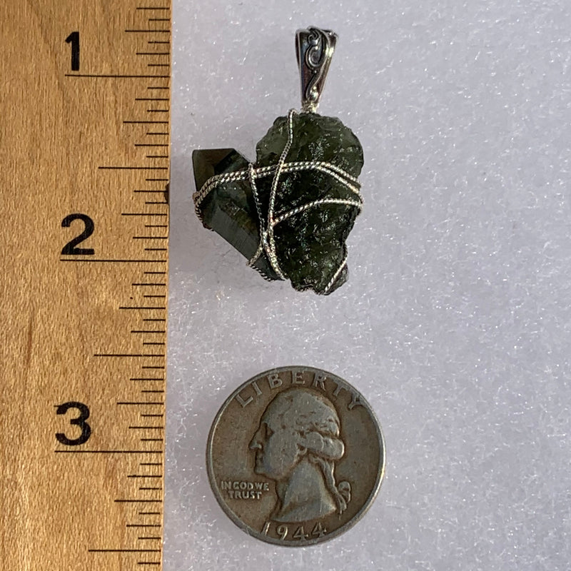 raw moldavite tektite and chlorite quartz crystal sterling silver wire wrapped pendant next to a ruler and US quarter for scale