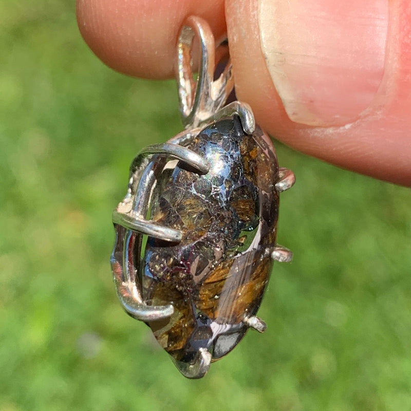 sterling silver sericho pallasite meteorite and raw moldavite tektite basket pendant held up on display to show details