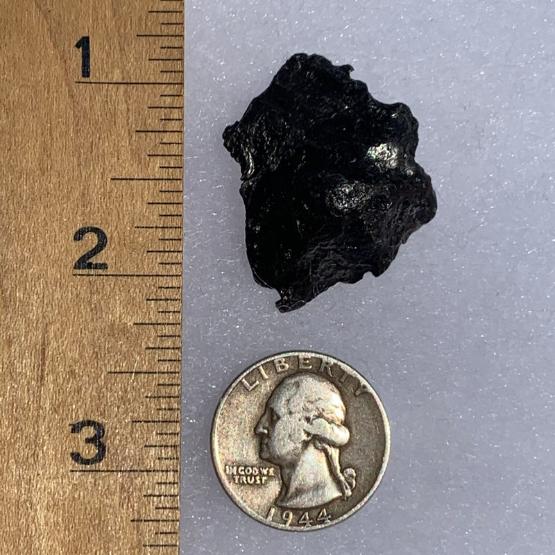 silver sikhote alin meteorite next to a ruler and US quarter for scale