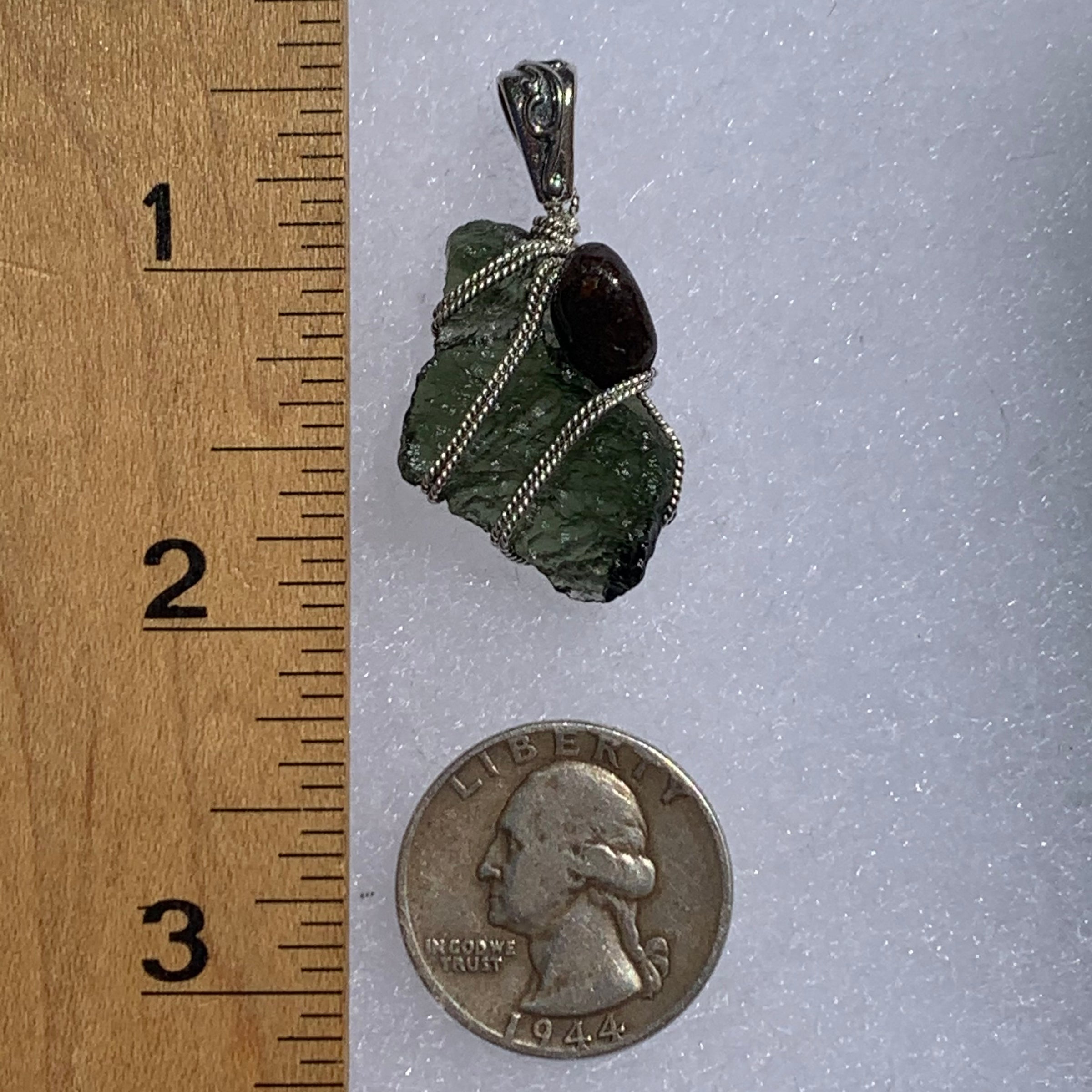 raw moldavite tektite and nwa 869 meteorite bead sterling silver wire wrapped pendant next to a ruler and US quarter for scale