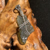 sterling silver wire wrapped raw moldavite tektite pendant sitting on driftwood for display