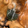 sterling silver wire wrapped raw moldavite tektite pendant sitting on driftwood for display