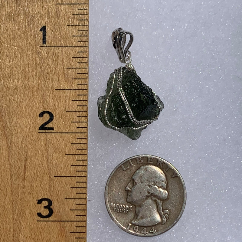 sterling silver wire wrapped raw moldavite tektite pendant next to a ruler and US quarter for scale