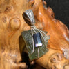 raw moldavite tektite and black tourmaline sterling silver wire wrapped pendant sitting on driftwood for display